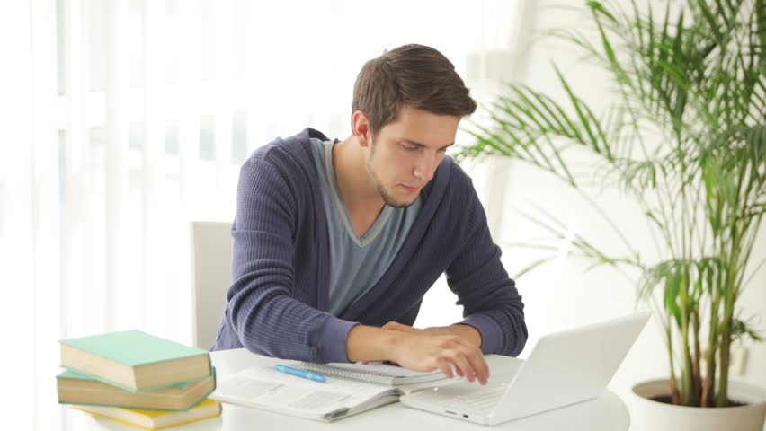 Handsome young man sitting at table with laptop and credit card