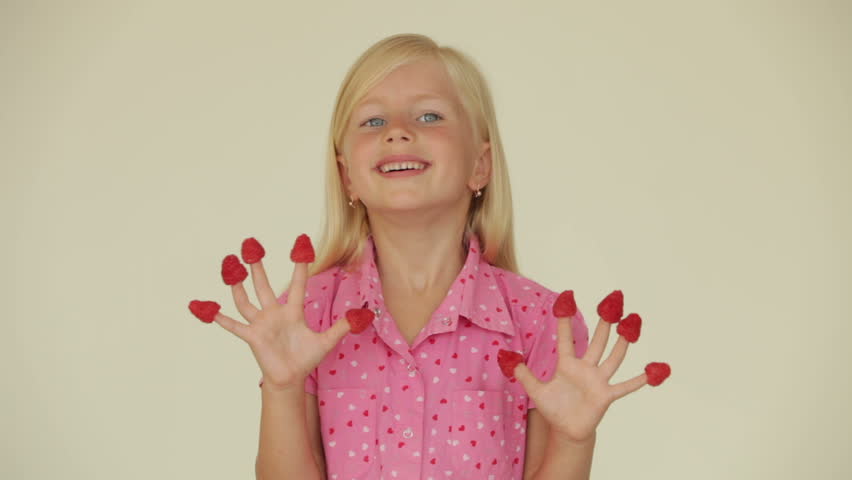 Funny little girl with raspberries on her fingers smiling at camera