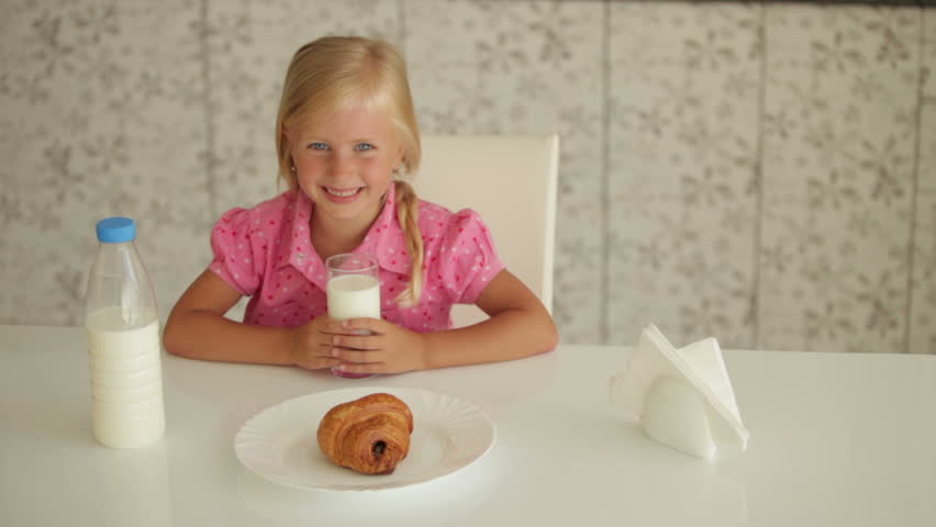 Pretty little girl sitting at kitchen table and gesturing with both hands