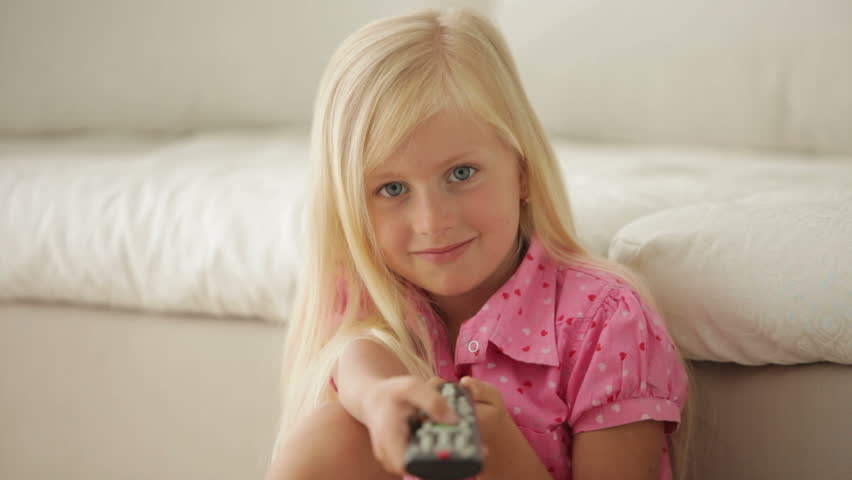 Pretty little girl sitting with remote control and smiling
