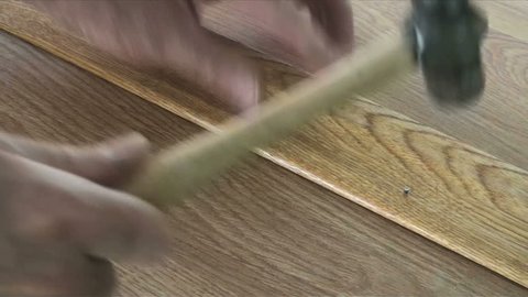 1920x1080 Woodworker hammers nail into wooden trim, finishes job by tapping head with nail puncher until it disappears.
