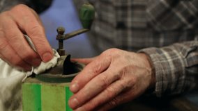 Elderly man cleaning an old coffee mill. Close up.