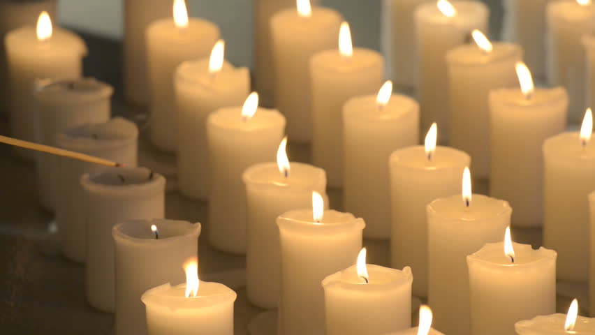 A Female Hand Lighting Up White Candles Aligned Vertically 