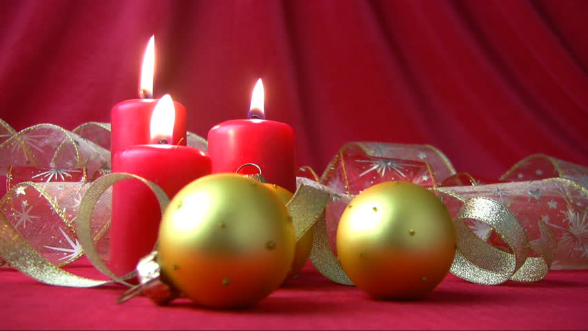 Gold Christmas balls and ribbons. Flame burning red candles trembles breath of