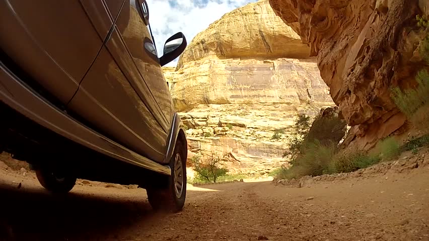An SUV driving through the beautiful desert of Capitol Reef National Park in