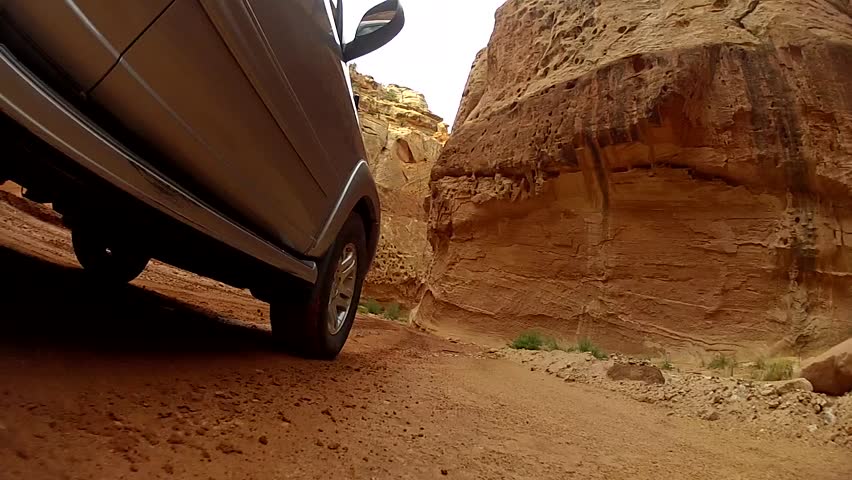An SUV driving through the beautiful desert of Capitol Reef National Park in