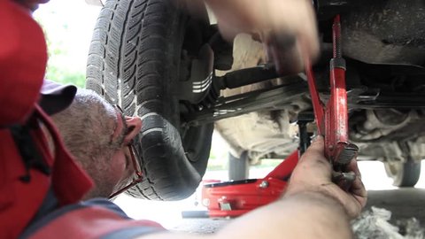 A car mechanic tightening a screw under a car/I am a car mechanic