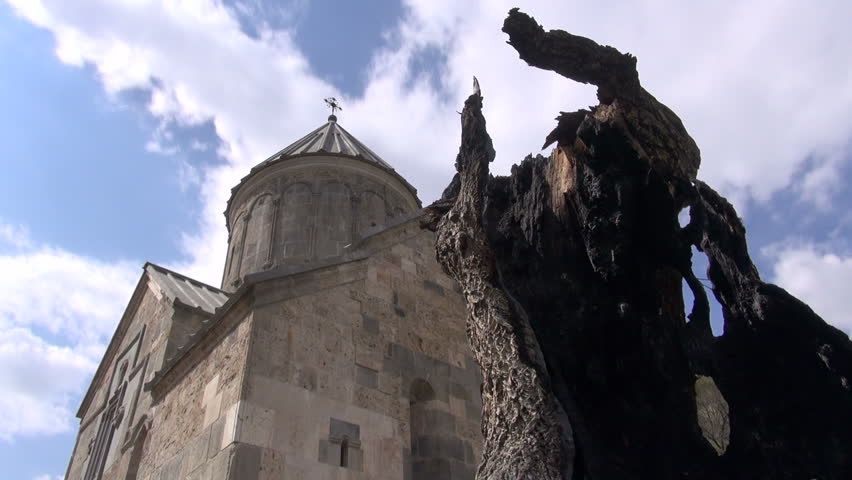 Timelapse video of clouds flying over Armenian monastery and a tree that has been burnt by fire