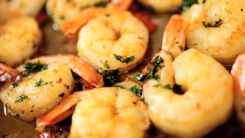 Close up of trasty fresh prawns with herbs browning in a saute pan in slow motion