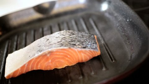 Fresh Sockeye salmon steaks being placed on a hot griddle to cook close up