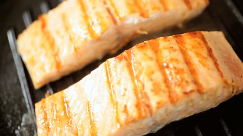 Fresh Sockeye salmon steaks being cooked on a griddle pan close up