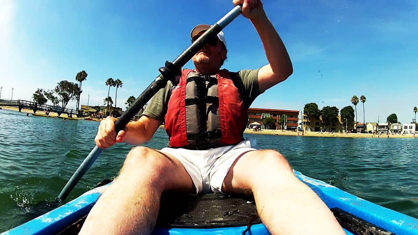 A middle aged man gets exercise and keeps fit by paddling a kayak or kayaking on