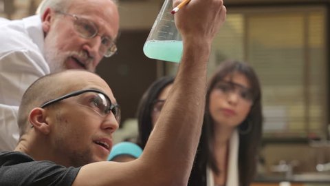 A college professor helps students understand a chemistry experiment