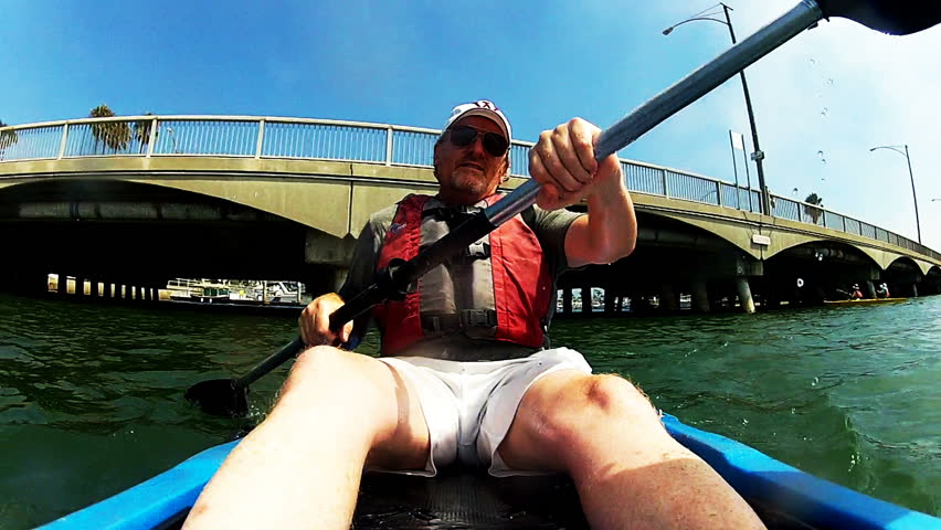 A mature man is exercising and keeping fit by paddling a sea kayak on Alamitos