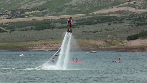 PARK CITY UTAH AUG 2013: Extreme Fly Board acrobatics on mountain lake recreation.Aerial machine personal watercraft allows propulsion underwater and in the air allowing a person to fly like Iron Man.