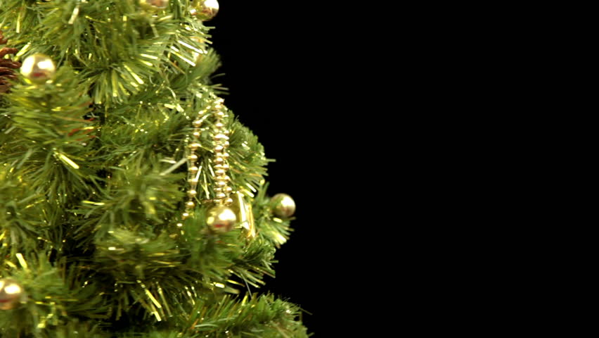Black background. Decorated Christmas tree rotates. Focus moves to the