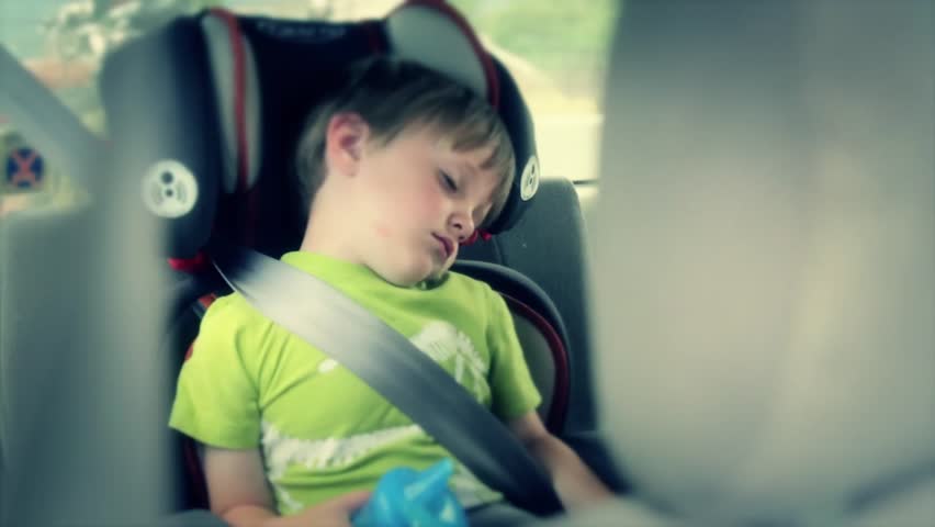 A toddler asleep in the car in his car seat