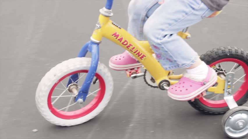 A little girl riding her bike with training wheels