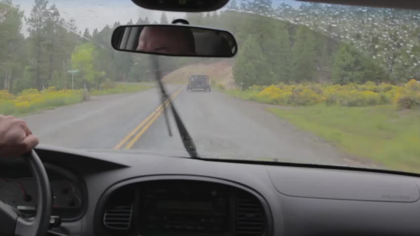 A man driving up a road in the rain