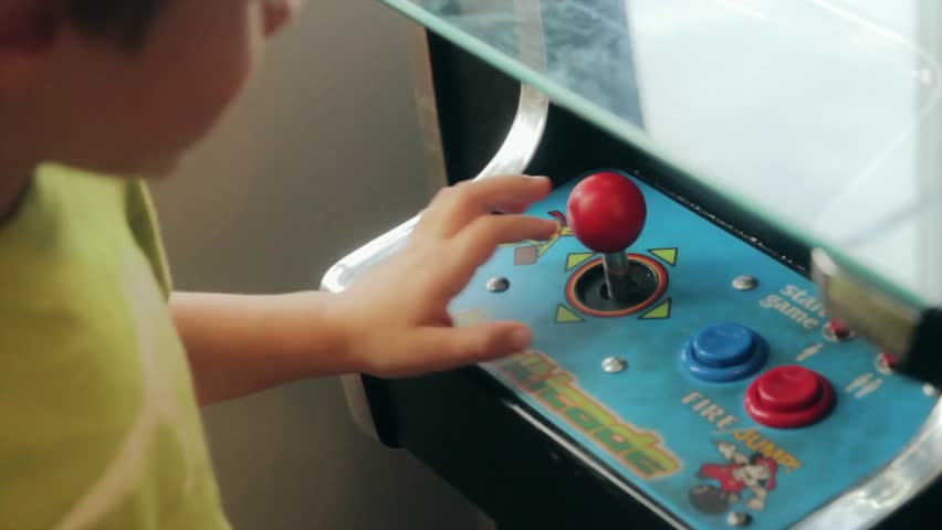A boy playing with an old arcade