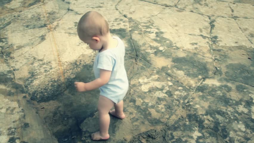 A baby boy playing in a puddle