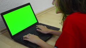 girl using computer with green screen for web and e-mail - Stock Video. Young beautiful teen laying down the floor and typing laptop. Dolly shoot.
