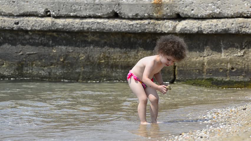 Beautiful baby child refreshing playfully on the sea beach - Stock Video.