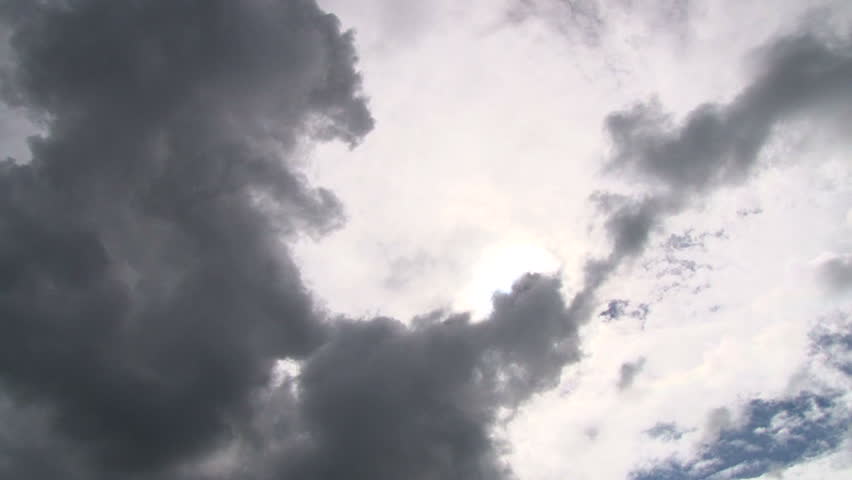 Cloudscape with bright sun shining while dark storm clouds pass, time lapse.