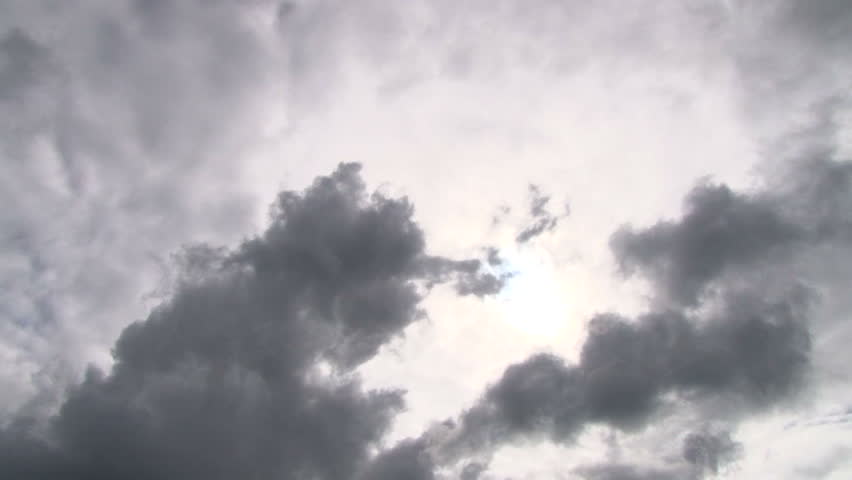 Cloudscape with sun shining behind dark storm clouds, time lapse.