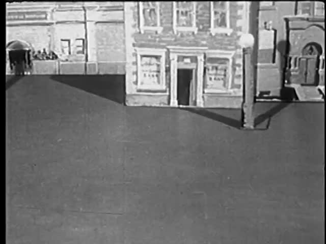 Person placing toy car in front of building model