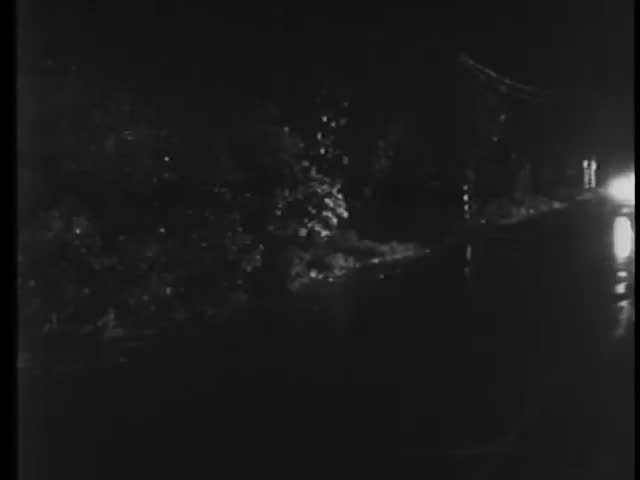 Car traveling on wet road at night, 1940s