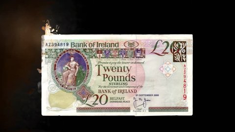 Burning Cash, Irish Pounds Sterling - 20 British Pounds Sterling (GBP) Bank of Ireland on a black background catches fire and disappears. 