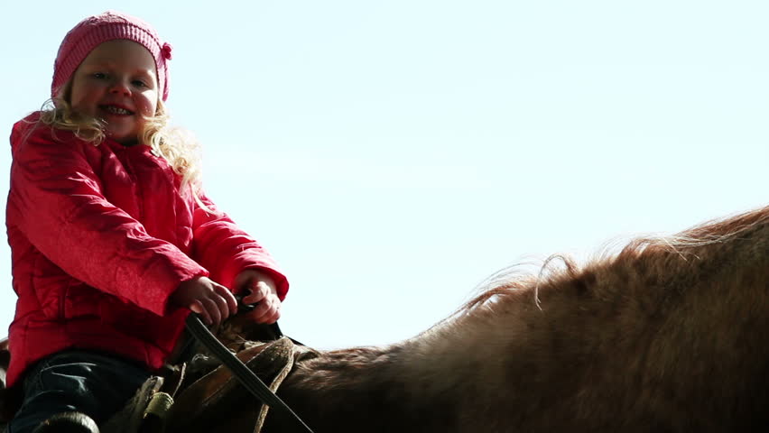 little girl sitting on a horse on nature