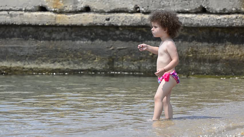 Beautiful baby child refreshing playfully on the sea beach - Stock Video.