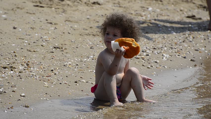 Summer beach Stock Video.  Summer beach with little child eating donut and