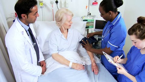 Older Caucasian female patient having blood pressure taken by a caring team of health care professionals