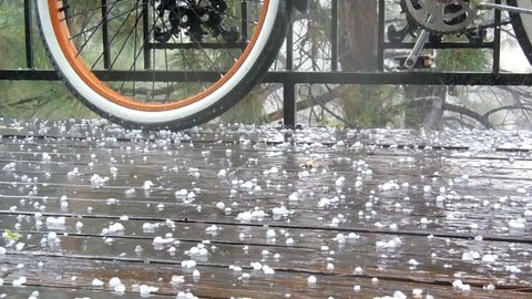 Rain and hail falling on a wooden balcony