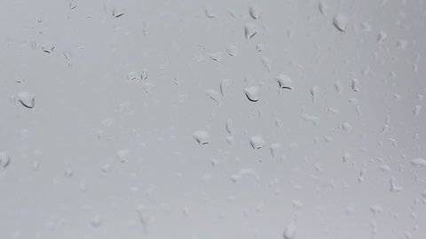 drops of water running down a wet glass surface