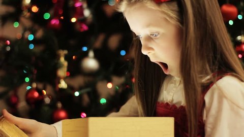 Christmas gift surprise - A little girl opens a Christmas present in amazement