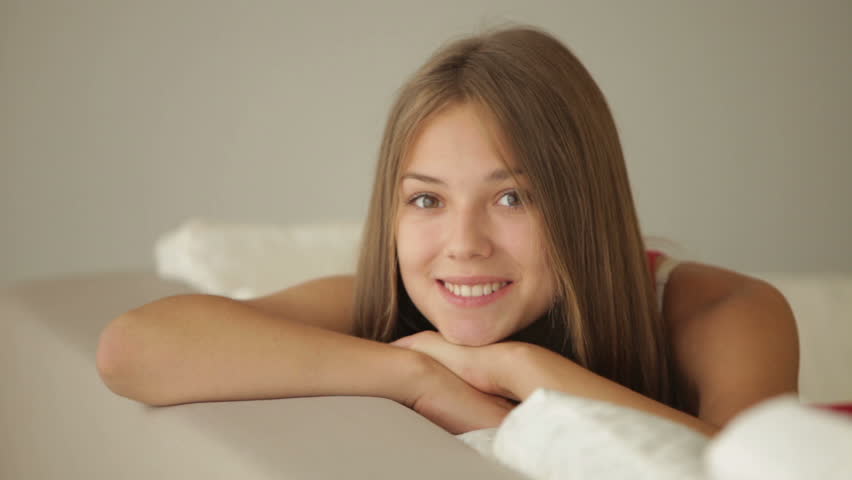 Charming girl relaxing on sofa looking at camera and smiling