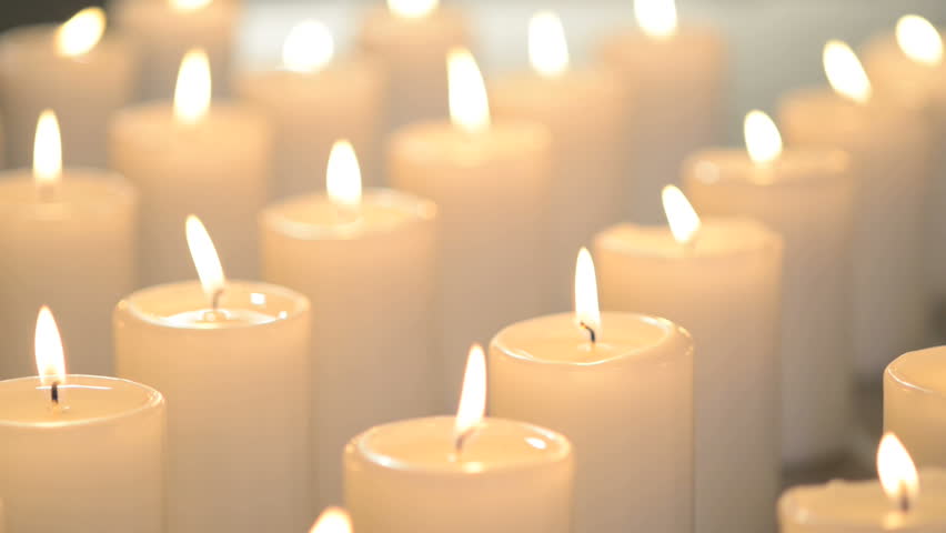 White Candles Burning Peacefully. One Candle In Focus, Other Candles Out Of