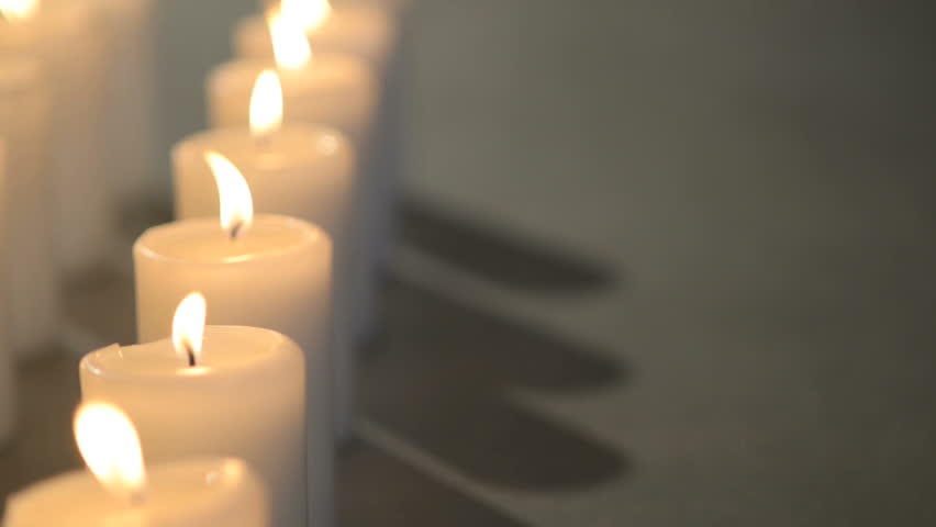 Dolly Shot Of Multiple White Candles Burning With Soft Candle Light. Aligned