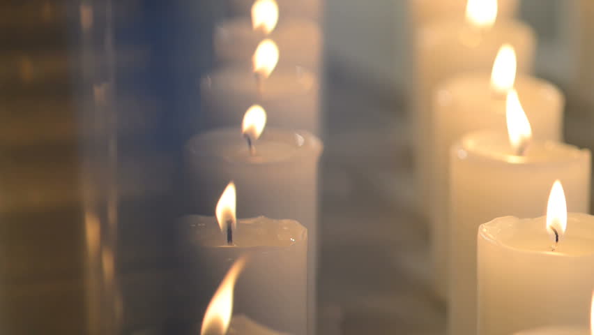 Dolly Shot Of White Candles Burning Aligned In Vertical Lines.