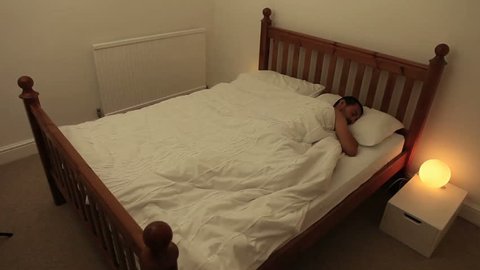 A man tosses and turns in bed during a restless night's sleep