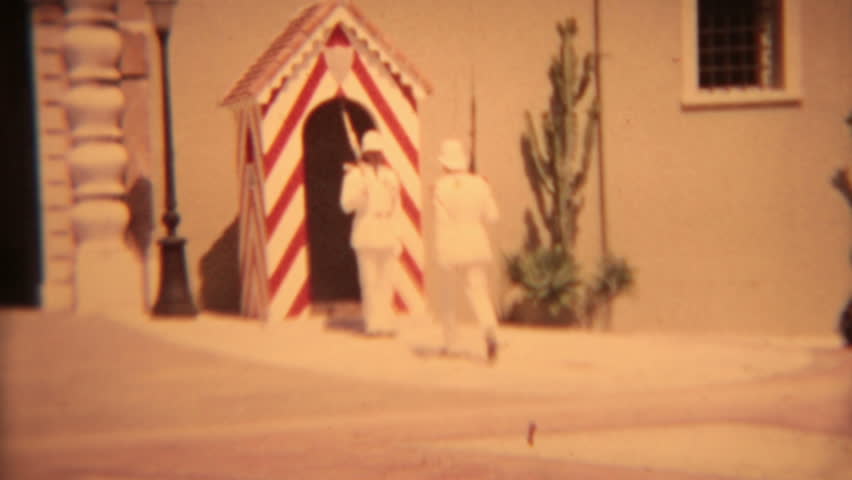 Changing of guard white uniforms Europe vintage film. 8mm home made movie of changing of guard in front of red and white guard house at large government building.