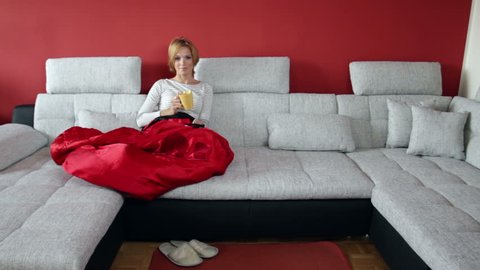 Young woman watching television on a huge sofa  in a modern apartment. High definition video.
