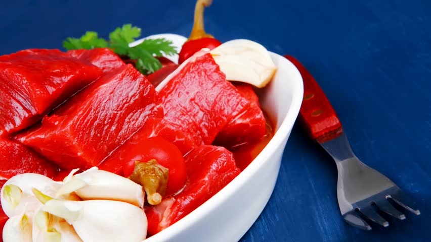 uncooked fresh beef meat chunks bowls with vegetables and red peppers serving on blue table with cutlery 1920x1080 intro motion slow hidef hd