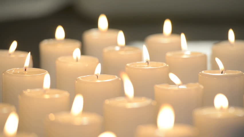 Edited Dolly Shot Of Multiple White Candles Burning With Soft Candle Light.
