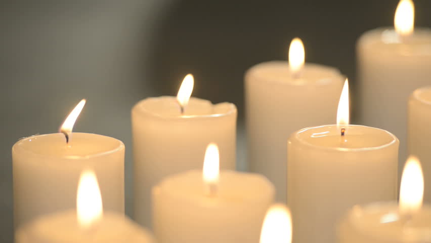 Dolly Shot Of White Candles Burning With Soft Candle Light On Black Background