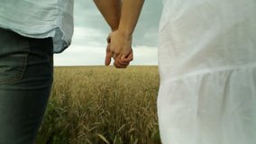 Couple walking then running across the cultivated land holding hands